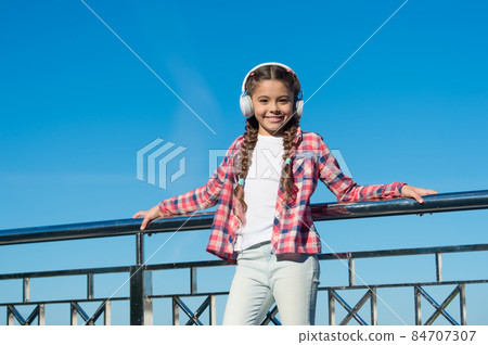 Girl child listen music outdoors with modern headphones Girl child listen music outdoors with modern headphones 84707307