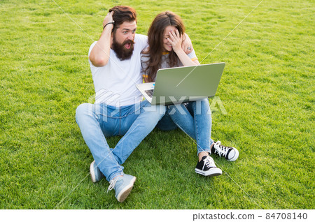 Cheerful couple use laptop sit green grass, shocking concent concept Cheerful couple use laptop sit green grass, shocking concent concept 84708140