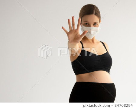 A pregnant woman wears a surgical mask to protect 84708294