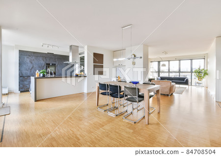 Spacious minimalist style dining room with table and chairs in modern apartment with white walls and wooden floor Spacious minimalist style dining room with table and chairs in modern apartment with white walls and wooden floor 84708504