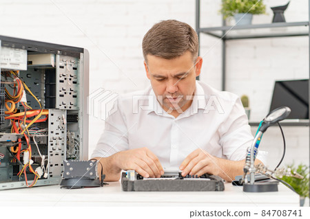 a man repairs motherboard. computer repair shop. professional services. a man repairs motherboard. computer repair shop. professional services. 84708741