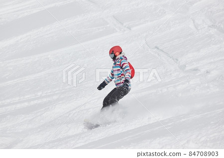 Female snowboarder on the slope, lot of fresh snow Female snowboarder on the slope, lot of fresh snow 84708903