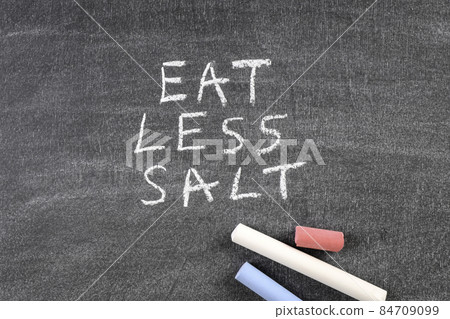 Colored pieces of chalk on a blackboard. Eat Less Salt 84709099