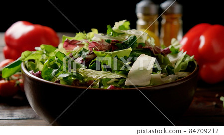 Mix of fresh green salad in a plate on the table with vegetables and spices. Mix of fresh green salad in a plate on the table with vegetables and spices. 84709212