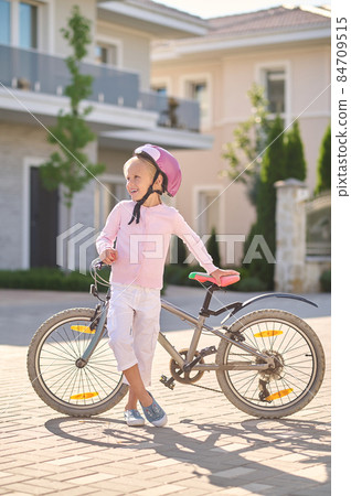A girl in helmet standing near the bike A girl in helmet standing near the bike 84709515