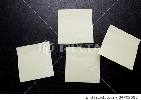 Stationery yellow stickers for inscription on a black leather isolated background. Blank sticker for reminder. Stationery yellow stickers for inscription on a black leather isolated background. Blank sticker for reminder. 84709688