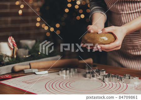 Merry Christmas, Happy New Year. Gingerbread cooking, cake, biscuit or strudel baking. Woman in apron is kneading dough. Girl gently holding, creases, cook and bake. Christmas decorations at kitchen 84709861