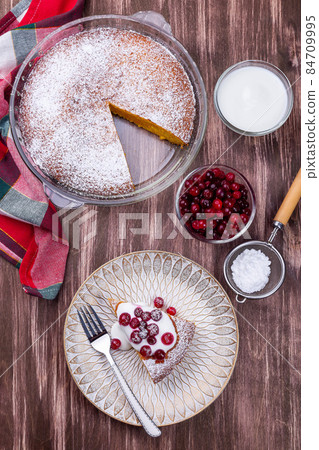 Piece of Swedish saffron Kladdkaka pie with white chocolate, whipping cream and cranberry, vertical Piece of Swedish saffron Kladdkaka pie with white chocolate, whipping cream and cranberry, vertical 84709995