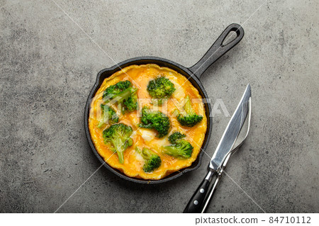 Healthy omelette with broccoli in cast iron pan top view 84710112