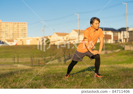 Middle-aged man stretching in the evening Middle-aged man stretching in the evening 84711406