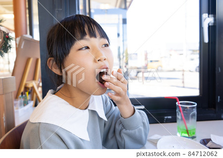 Elementary school girl eating a snack donut Elementary school girl eating a snack donut 84712062