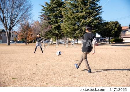 Elementary school boy playing soccer in a park in the blue sky Elementary school boy playing soccer in a park in the blue sky 84712063