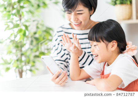 Parents and children (mother and child) enjoying together on their smartphones 84712787