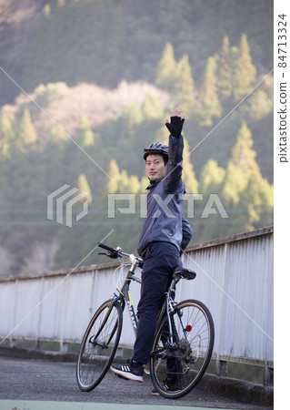Male cyclist raising his hand 84713324