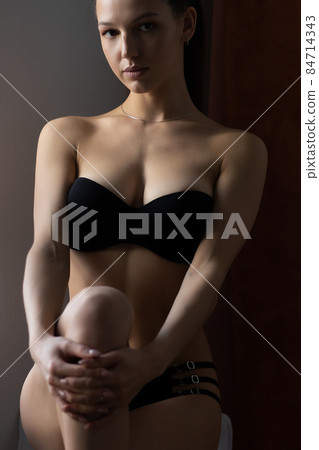 Alluring woman in underwear leaning on wall near window Alluring woman in underwear leaning on wall near window 84714343