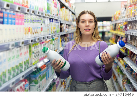 young woman choosing dairy products in supermarket 84716449