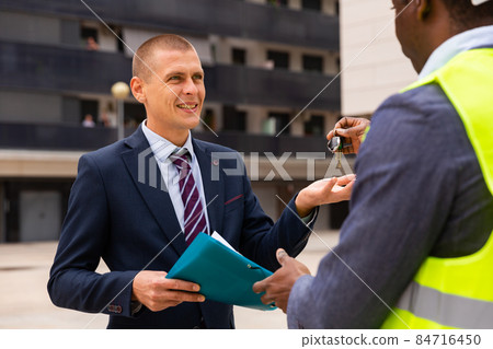 Commissioning of new shopping center - businessman and builder exchange keys and documents 84716450