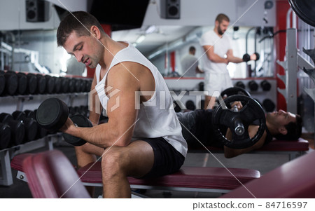 Man exercising with dumbbells in gym Man exercising with dumbbells in gym 84716597