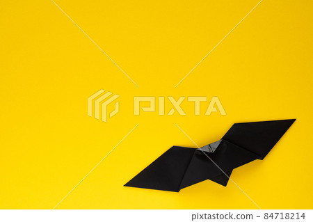 Black origami bat on yellow background 84718214