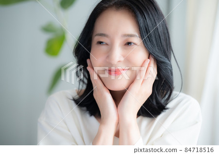 A beautiful Japanese woman who cares about her skin condition and smiles in front of her looking at the camera 84718516