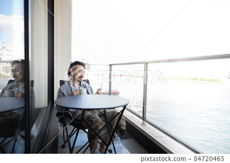 Japanese man looking at a smartphone while relaxing on the veranda 6 Japanese man looking at a smartphone while relaxing on the veranda 6 84720465