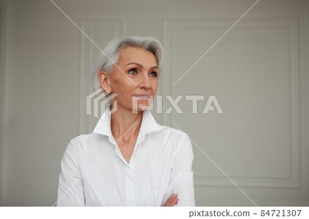 Close up portrait of beautiful older woman standing by wall Close up portrait of beautiful older woman standing by wall 84721307