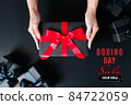 Boxing Day sale, woman hand give the gift box on black background 84722059