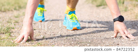 Active man in low starting position prepares for sprint in park 84722352