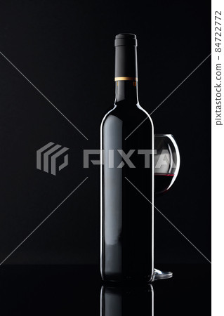 Bottle and glass of red wine on a black background. 84722772