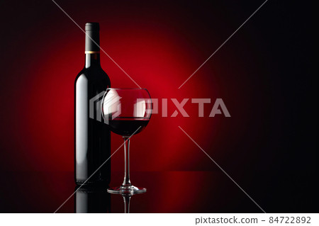 Glass and bottle of red wine on a black reflective background. Copy space. Glass and bottle of red wine on a black reflective background. Copy space. 84722892