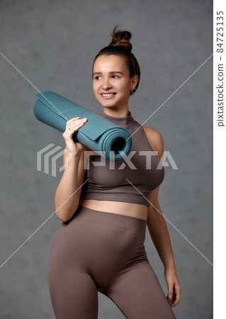 Smiling pregnant woman in sportswear ready for morning gymnastics or exercise. Happy young female follow healthy lifestyle during pregnancy, hold yoga mat for Pilates or stretching 84725135