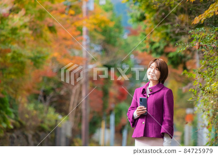 秋天風景中帶著智能手機的女人 秋天風景中帶著智能手機的女人 84725979