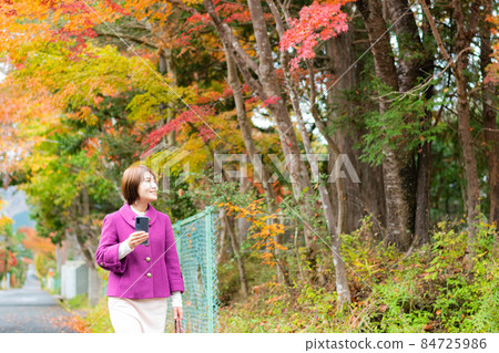 秋天風景中帶著智能手機的女人 秋天風景中帶著智能手機的女人 84725986
