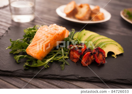 Baked sea trout fillet with fresh vegetables and herbs on black board Baked sea trout fillet with fresh vegetables and herbs on black board 84726033