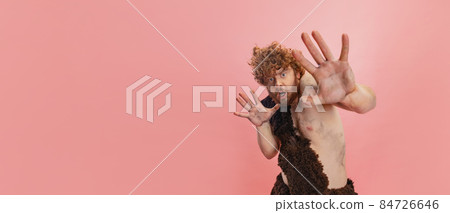Cropped portrait of man in character of neandertal showing fear isolated over pink background. Flyer 84726646