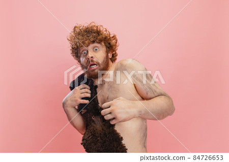 Cropped portrait of man in character of neandertal stepping back in fear isolated over pink background 84726653