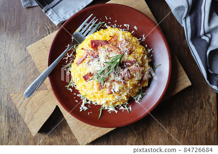 Risotto with pumpkin and bacon on a dark wooden table. Top view 84726684