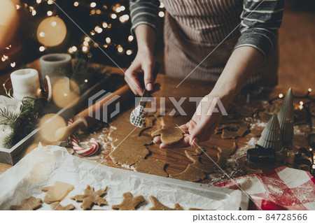 Merry Christmas, Happy New Year. Gingerbread cookies cooking, baking. Young woman sculpts, cuts and carves gingerbread cookie figures from kneaded dough using special kitchen forms. High quality photo 84728566