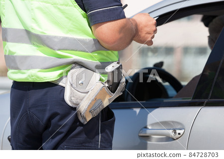 Police officer is checking the driving license of a car driver during a traffic control 84728703