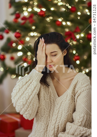Bad Christmas Gift - Disappointed and Unhappy Woman During Winter Holidays Indoors at Home Bad Christmas Gift - Disappointed and Unhappy Woman During Winter Holidays Indoors at Home 84731128