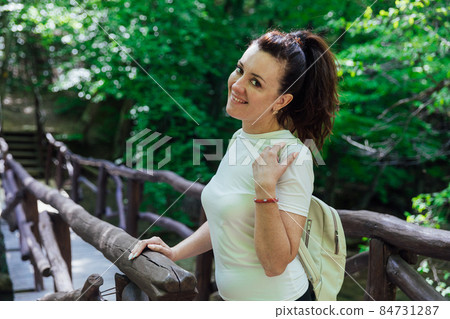 beautiful tourist woman walking through the green forest on a journey 84731287
