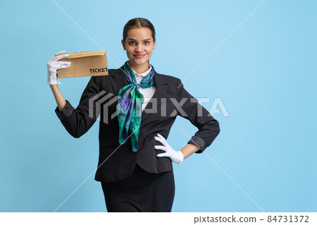 Half-length portrait of beautiful young girl, flight attendant in black uniform posing isolated on blue studio background. Half-length portrait of beautiful young girl, flight attendant in black uniform posing isolated on blue studio background. 84731372