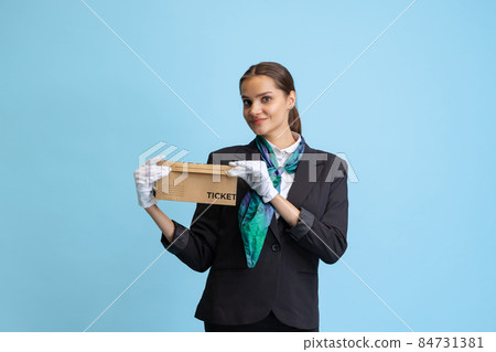 Half-length portrait of beautiful young girl, flight attendant in black uniform posing isolated on blue studio background. Half-length portrait of beautiful young girl, flight attendant in black uniform posing isolated on blue studio background. 84731381