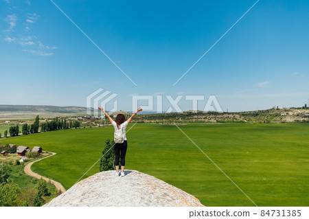 woman traveler on top of a mountain alone looks at the landscape woman traveler on top of a mountain alone looks at the landscape 84731385