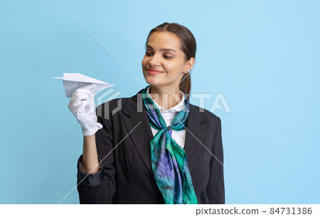 Half-length portrait of beautiful young girl, flight attendant in black uniform posing isolated on blue studio background. Half-length portrait of beautiful young girl, flight attendant in black uniform posing isolated on blue studio background. 84731386