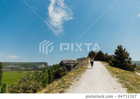 woman traveler on top of a mountain alone looks at the landscape woman traveler on top of a mountain alone looks at the landscape 84731387