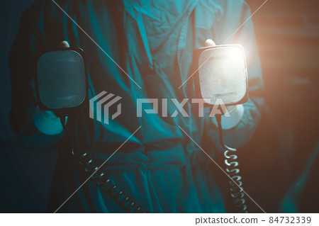 Doctor holding manual Defibrillator for Pulse generator in operating room Doctor holding manual Defibrillator for Pulse generator in operating room 84732339