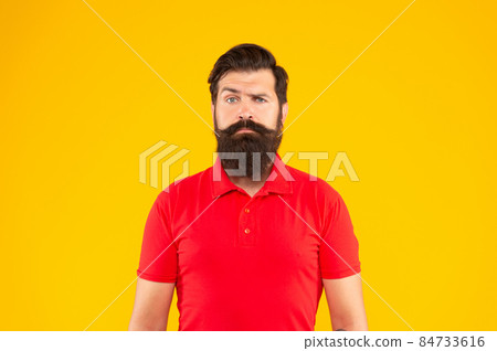 serious bearded man with moustache in tshirt on yellow background, face serious bearded man with moustache in tshirt on yellow background, face 84733616