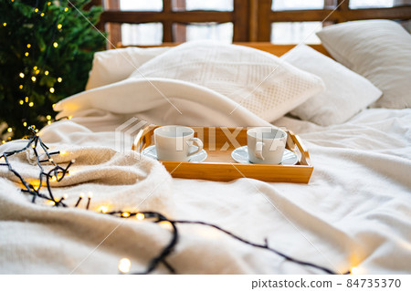 A wooden tray for eating in bed with two white tea cups. A wooden tray for eating in bed with two white tea cups. 84735370