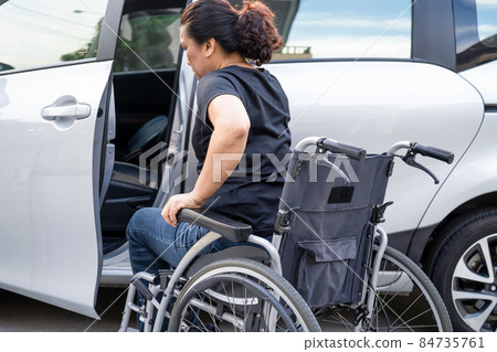 Asian woman folding and lift up wheelchair into her car. Accessibility concept. Asian woman folding and lift up wheelchair into her car. Accessibility concept. 84735761
